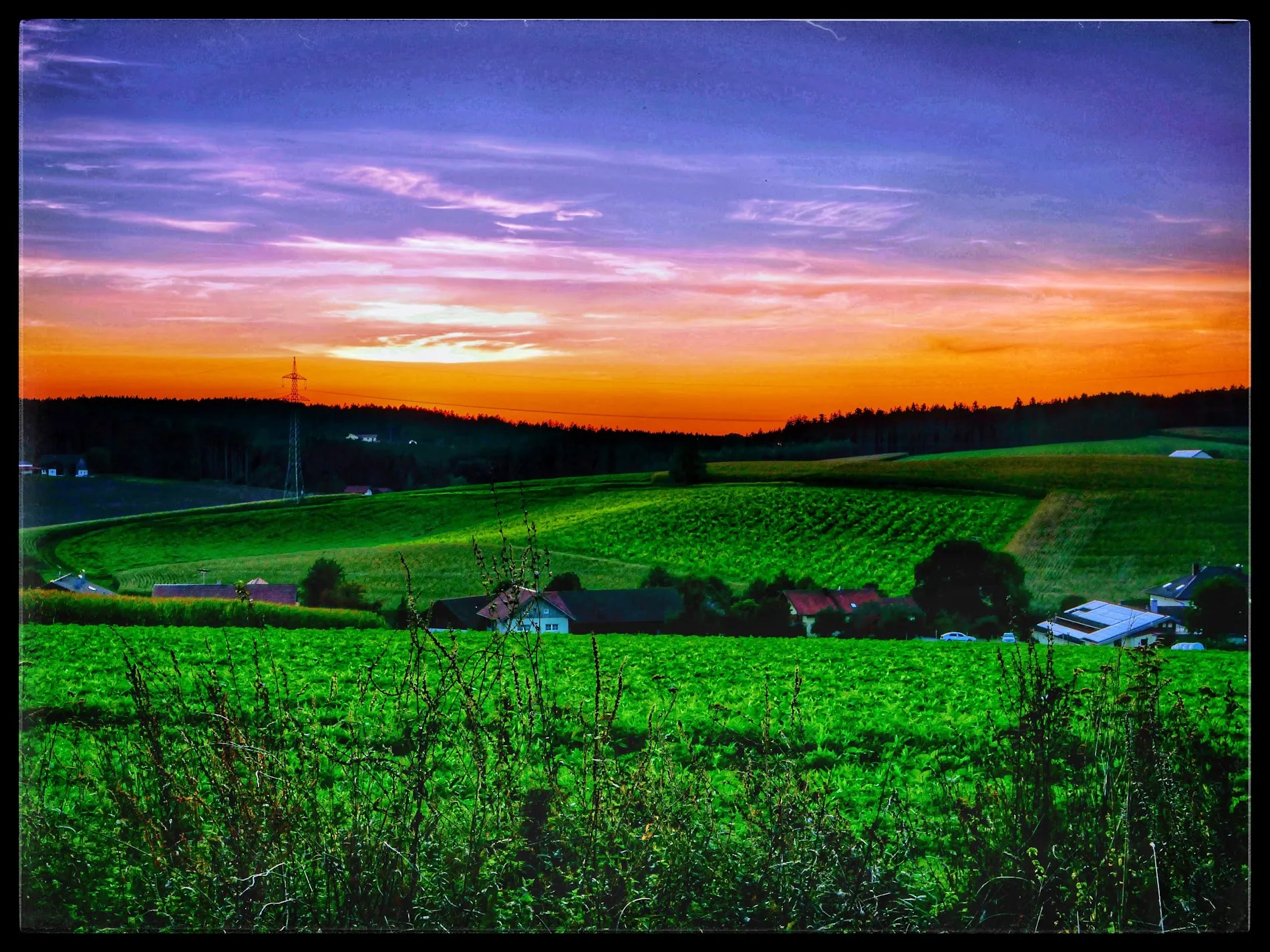 Bunter Sonnenuntergang über Feldern und Dorf